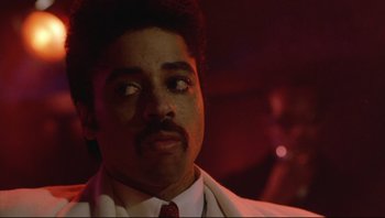 Movie still from “Purple Rain” (1984), directed by Albert Magnoli – A person wearing a suit and tie; Close Up shot, Low angle