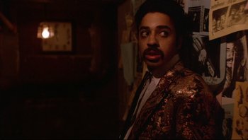 Movie still from “Purple Rain” (1984), directed by Albert Magnoli – A man in a jacket and tie standing in a room; Close Up shot, Low angle