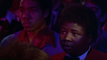 Movie still from “Purple Rain” (1984), directed by Albert Magnoli – Two young men sitting next to each other at a party; Close Up shot, Low angle