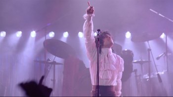 Movie still from “Purple Rain” (1984), directed by Albert Magnoli – A man in a white shirt is on a stage; Medium shot, Low angle
