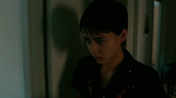 Movie still from “Pusher” (1996), directed by Nicolas Winding Refn – A young man in a black shirt is looking at the camera; Close Up shot, High angle