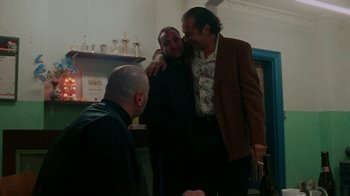 Movie still from “Pusher” (1996), directed by Nicolas Winding Refn – A group of men standing next to each other in a room; Medium shot, Low angle