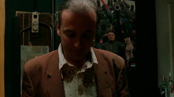 Movie still from “Pusher” (1996), directed by Nicolas Winding Refn – A man in a brown jacket and a white shirt; Close Up shot, Low angle