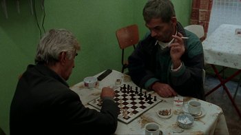 Movie still from “Pusher” (1996), directed by Nicolas Winding Refn – Two men are playing a game of chess on a table; Medium shot, High angle
