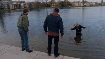 Movie still from “Pusher” (1996), directed by Nicolas Winding Refn – Two men standing on the edge of the water watching a man in the water; Wide shot, High angle