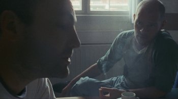Movie still from “Pusher” (1996), directed by Nicolas Winding Refn – Two men sitting at a table with a cup of coffee; Medium shot, Over the shoulder angle
