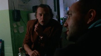 Movie still from “Pusher” (1996), directed by Nicolas Winding Refn – Two men sitting in a room talking to each other; Close Up shot, Over the shoulder angle