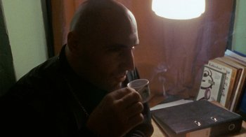 Movie still from “Pusher” (1996), directed by Nicolas Winding Refn – A bald man is drinking a cup of coffee; Close Up shot, Low angle