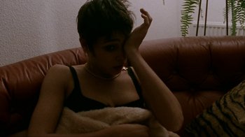 Movie still from “Pusher” (1996), directed by Nicolas Winding Refn – A woman sitting on a couch with her hand on her face; Close Up shot, High angle