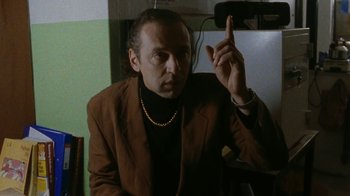 Movie still from “Pusher” (1996), directed by Nicolas Winding Refn – A man in a brown jacket is pointing up; Medium shot, Low angle