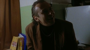 Movie still from “Pusher” (1996), directed by Nicolas Winding Refn – A man in a brown jacket is smiling for the camera; Close Up shot, Low angle