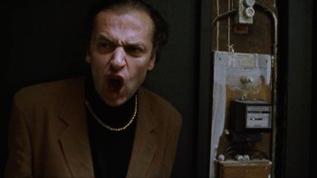 Movie still from “Pusher” (1996), directed by Nicolas Winding Refn – A man in a brown jacket and a gold chain; Close Up shot, Low angle