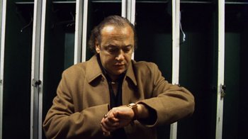 Movie still from “Pusher III” (2005), directed by Nicolas Winding Refn – A man looking at his watch while standing on a train; Medium shot, Low angle