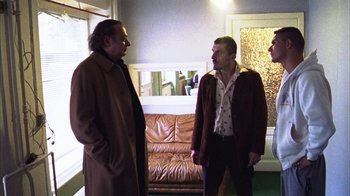 Movie still from “Pusher III” (2005), directed by Nicolas Winding Refn – Three men are standing in a room talking; Medium shot, Low angle