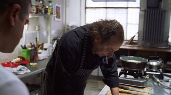 Movie still from “Pusher III” (2005), directed by Nicolas Winding Refn – A man standing in front of an oven in a kitchen; Medium shot, High angle