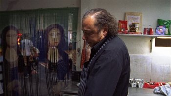 Movie still from “Pusher III” (2005), directed by Nicolas Winding Refn – A man standing in front of a picture of a woman; Medium shot, Over the shoulder angle