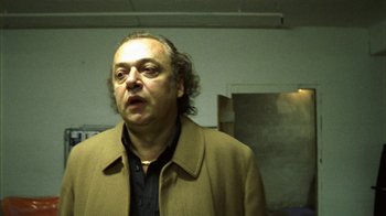 Movie still from “Pusher III” (2005), directed by Nicolas Winding Refn – A man in a brown jacket is looking at the camera; Close Up shot, Low angle
