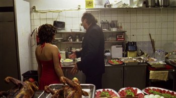 Movie still from “Pusher III” (2005), directed by Nicolas Winding Refn – A man and a woman standing in a kitchen preparing food; Medium shot, Over the shoulder angle