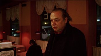 Movie still from “Pusher III” (2005), directed by Nicolas Winding Refn – A man standing in front of a window at a restaurant; Close Up shot, Low angle
