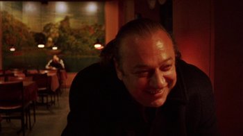 Movie still from “Pusher III” (2005), directed by Nicolas Winding Refn – A person smiling at the camera; Close Up shot, Over the shoulder angle