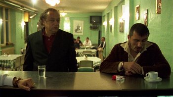Movie still from “Pusher III” (2005), directed by Nicolas Winding Refn – Two men are sitting at a table in a restaurant; Medium shot, Low angle
