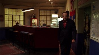 Movie still from “Pusher III” (2005), directed by Nicolas Winding Refn – A man wearing a suit and tie in a room; Wide shot, Low angle