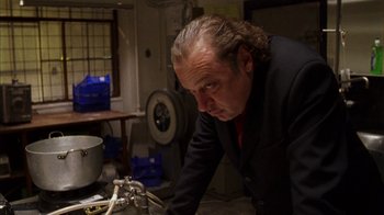 Movie still from “Pusher III” (2005), directed by Nicolas Winding Refn – A man in a black suit and red tie looking at a pipe; Close Up shot, Low angle