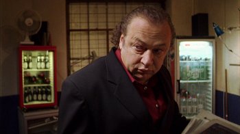 Movie still from “Pusher III” (2005), directed by Nicolas Winding Refn – An older man in a black suit and red shirt; Close Up shot, Low angle