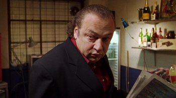 Movie still from “Pusher III” (2005), directed by Nicolas Winding Refn – A man in a black jacket and red shirt; Close Up shot, Low angle