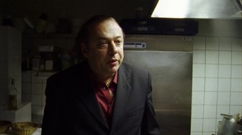 Movie still from “Pusher III” (2005), directed by Nicolas Winding Refn – A man wearing a suit and tie in a kitchen; Close Up shot, Low angle