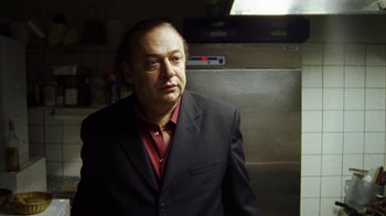 Movie still from “Pusher III” (2005), directed by Nicolas Winding Refn – A man wearing a suit and a red shirt; Close Up shot, Low angle