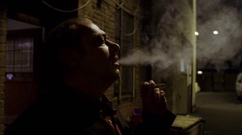 Movie still from “Pusher III” (2005), directed by Nicolas Winding Refn – A man is smoking a cigarette in the dark; Close Up shot, Low angle