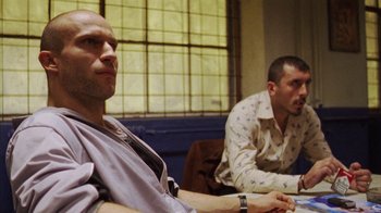 Movie still from “Pusher III” (2005), directed by Nicolas Winding Refn – Two men are sitting in a room and one of them has a watch on his wrist; Close Up shot, Low angle