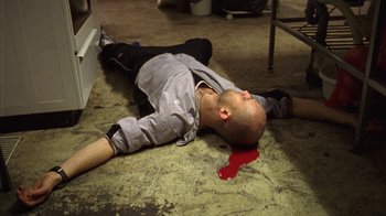 Movie still from “Pusher III” (2005), directed by Nicolas Winding Refn – A man laying on the ground with blood on the floor; Medium shot, Overhead angle
