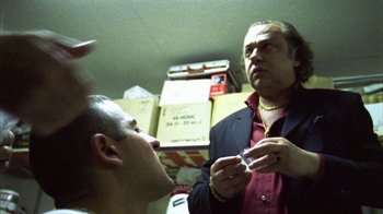 Movie still from “Pusher III” (2005), directed by Nicolas Winding Refn – A man is looking at another man in a room; Close Up shot, Low angle