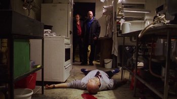 Movie still from “Pusher III” (2005), directed by Nicolas Winding Refn – A man is lying on the ground in a kitchen; Wide shot, High angle