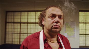 Movie still from “Pusher III” (2005), directed by Nicolas Winding Refn – A man in a red shirt is smoking a cigarette; Close Up shot, Low angle