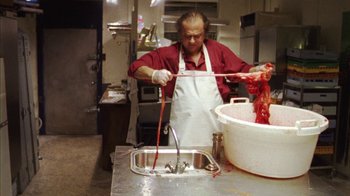 Movie still from “Pusher III” (2005), directed by Nicolas Winding Refn – A man in an apron is preparing food in a kitchen; Medium shot, High angle