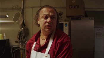 Movie still from “Pusher III” (2005), directed by Nicolas Winding Refn – A man in a red shirt and white apron in a kitchen; Close Up shot, Low angle