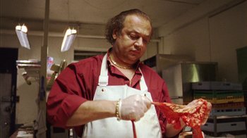 Movie still from “Pusher III” (2005), directed by Nicolas Winding Refn – A man in a red shirt and white apron holding a knife; Medium shot, Low angle