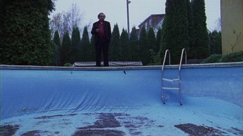 Movie still from “Pusher III” (2005), directed by Nicolas Winding Refn – A man standing on the edge of an empty swimming pool; Wide shot, High angle