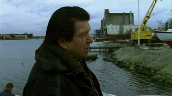 Movie still from “Pusher II” (2004), directed by Nicolas Winding Refn – A person near a body of water; Medium shot, Over the shoulder angle