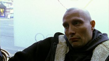 Movie still from “Pusher II” (2004), directed by Nicolas Winding Refn – A man in a black jacket is looking at the camera; Close Up shot, Low angle