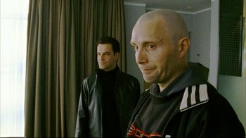 Movie still from “Pusher II” (2004), directed by Nicolas Winding Refn – Two men standing next to each other in front of a curtain; Close Up shot, Over the shoulder angle