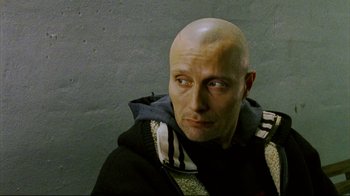 Movie still from “Pusher II” (2004), directed by Nicolas Winding Refn – A man with a bald head is looking at the camera; Close Up shot, High angle