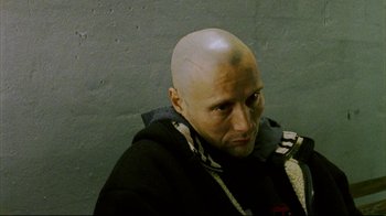 Movie still from “Pusher II” (2004), directed by Nicolas Winding Refn – A man with bald head is looking at the camera; Close Up shot, High angle