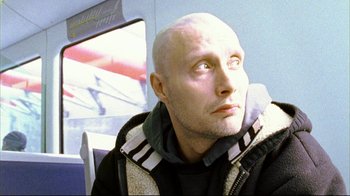Movie still from “Pusher II” (2004), directed by Nicolas Winding Refn – A man with a bald head looking upward; Close Up shot, Low angle