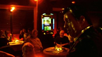 Movie still from “Pusher II” (2004), directed by Nicolas Winding Refn – A group of people sitting at a table in a room; Medium shot, Low angle