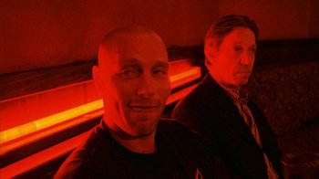 Movie still from “Pusher II” (2004), directed by Nicolas Winding Refn – Two men sitting in front of one another in a red light; Close Up shot, Over the shoulder angle