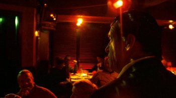 Movie still from “Pusher II” (2004), directed by Nicolas Winding Refn – A group of people sitting at a table in a room; Close Up shot, Low angle